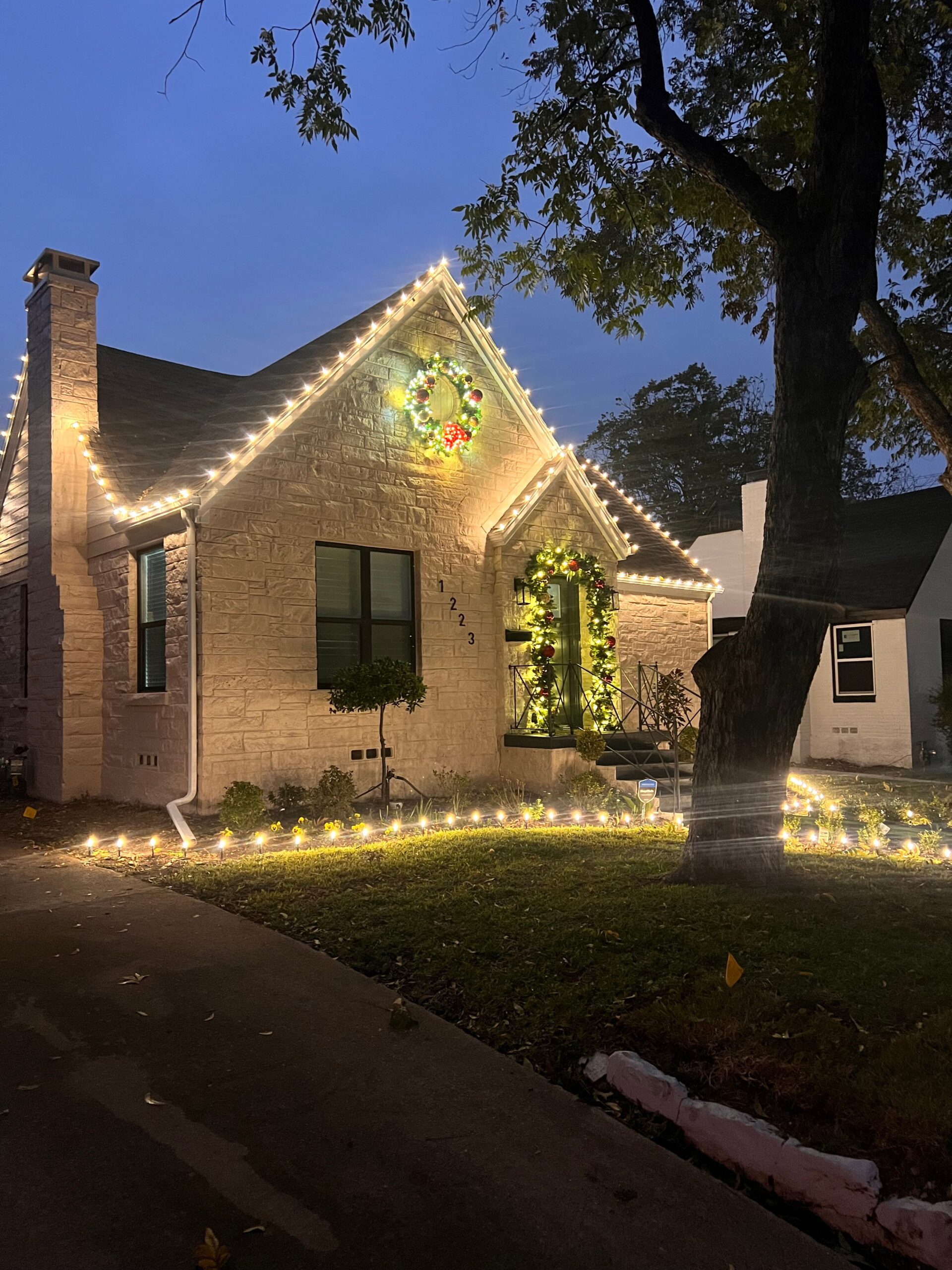 Front of a house in Dallas featuring holiday decor installed by Christmas Lights 4 U. Design includes decorative wreath and decorative garland over front doorway.